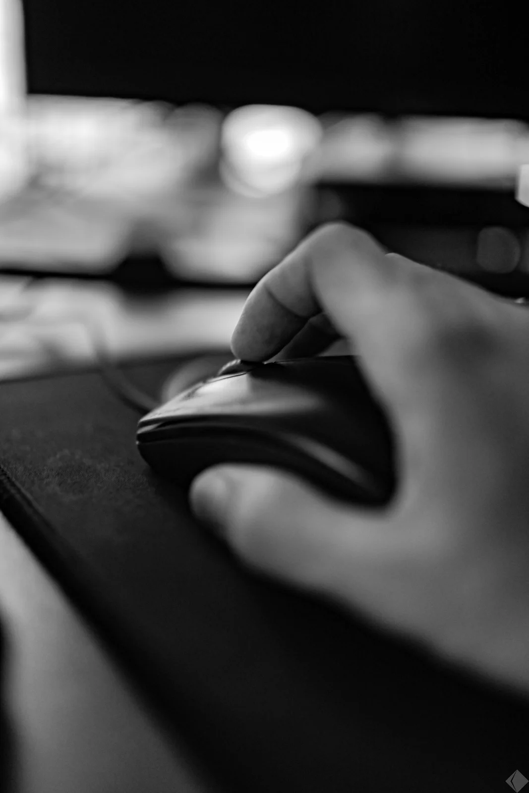 Close-up black and white photo of a finger resting on a mouse button, about to click.